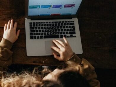 person using macbook pro on brown wooden floor